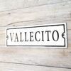 Cartel enlozado 20x7 cm fondo blanco texto "VALLECITO" en negro